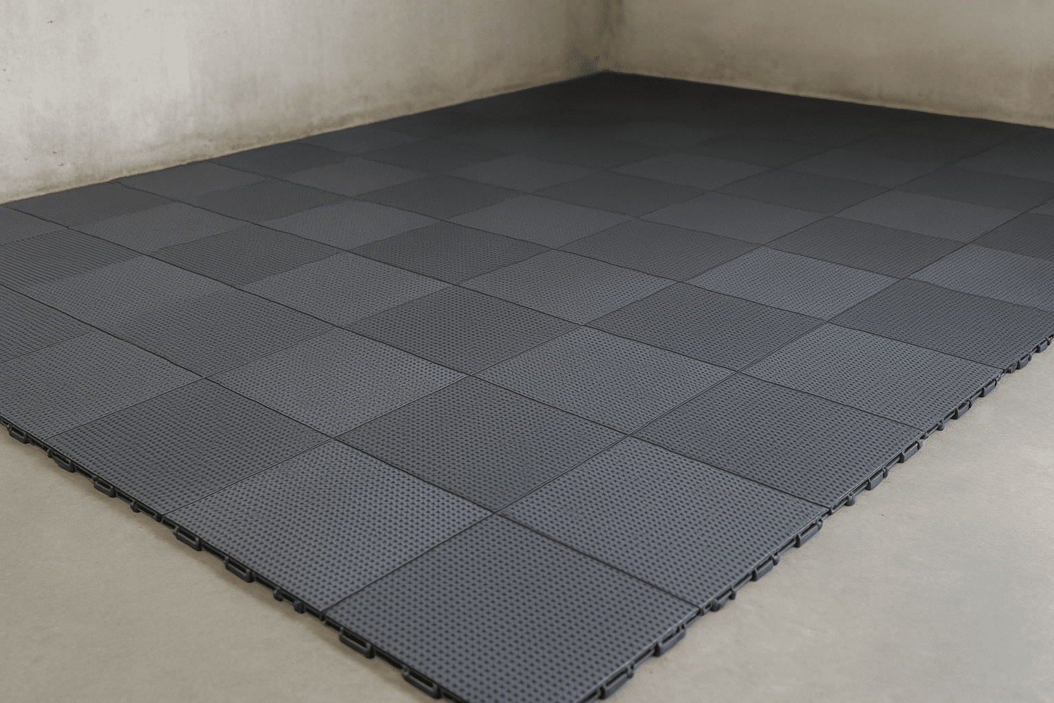 Dalle clipsable de sol pour garage en PVC gris foncé, posée en surface régulière avec système d’assemblage modulaire visible, adaptée aux charges lourdes.